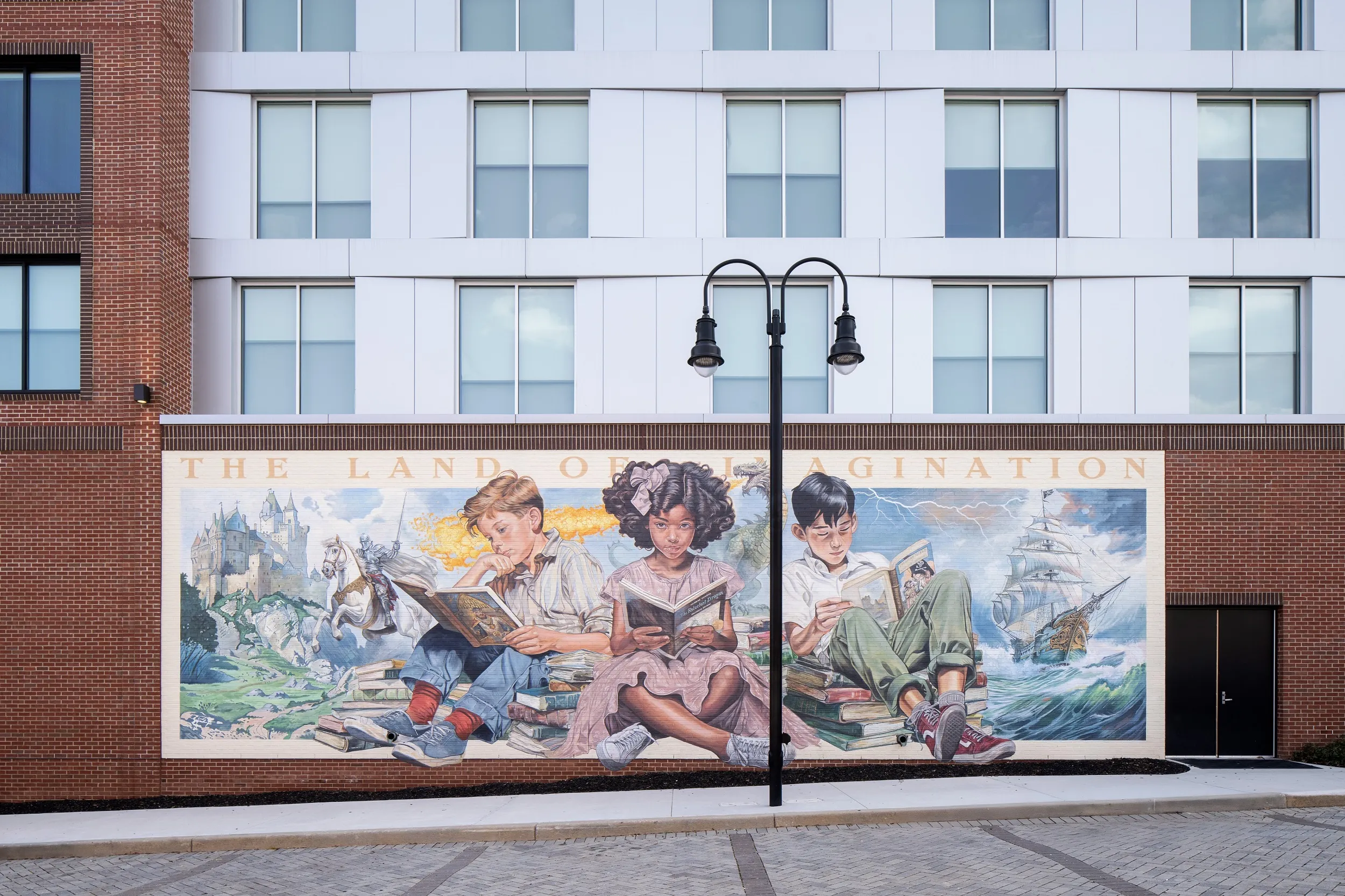 hotel building with mural of three young children immersed in the magic of reading